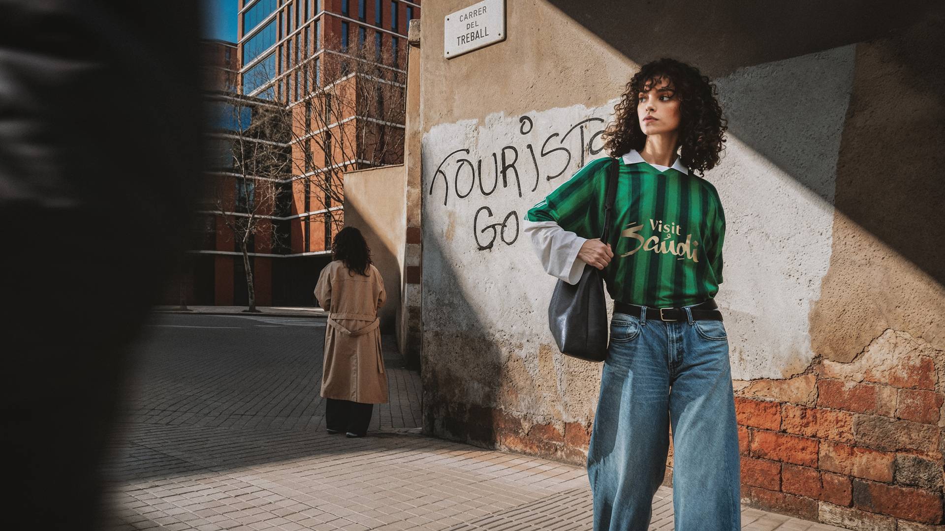 Traveler standing beside a wall with tourists go home graffiti